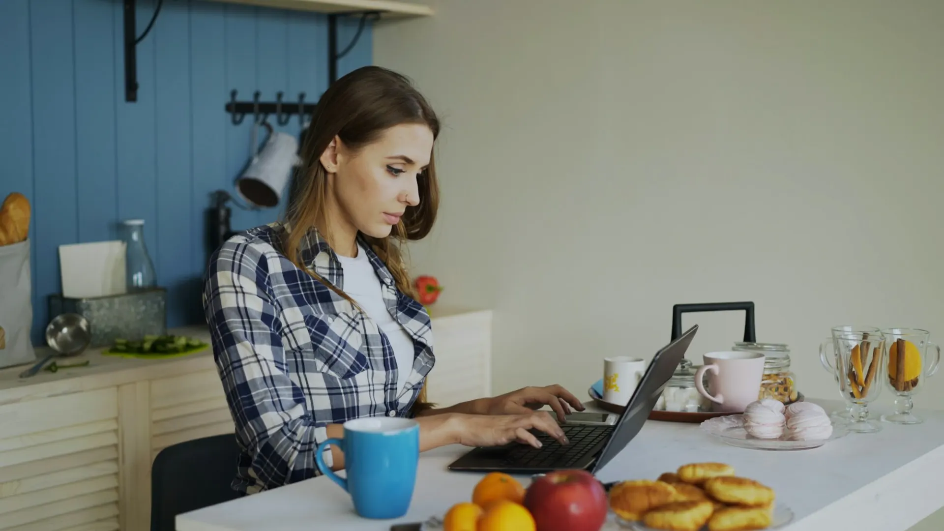 Iemand aan een laptop aan de keukentafel